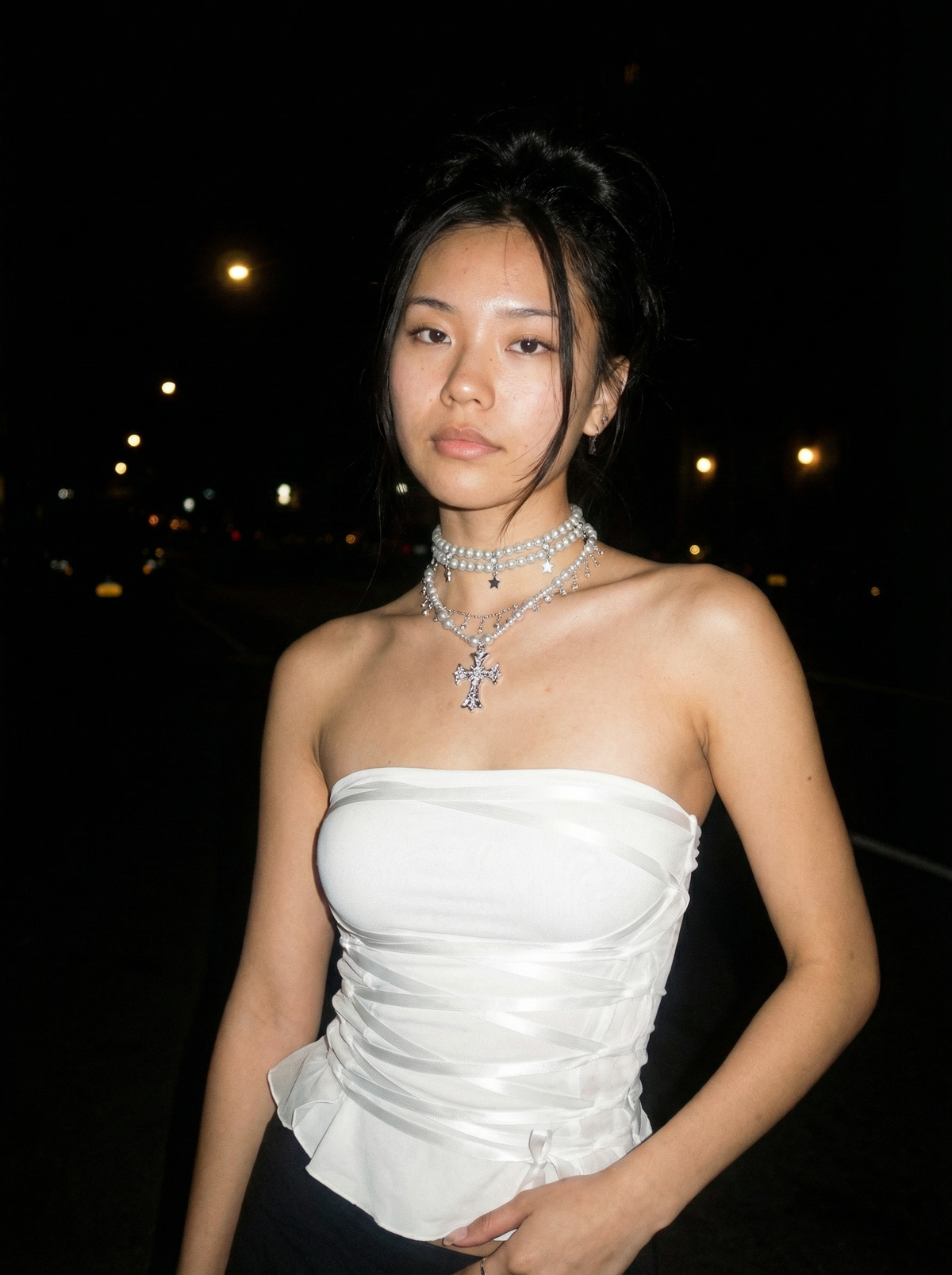 Model wearing the Cathedral Chain integrated multi-strand gothic pearl cross choker necklace with gunmetal faux pearls, layered silver-tone chains, and an ornate cross pendant outdoors at night