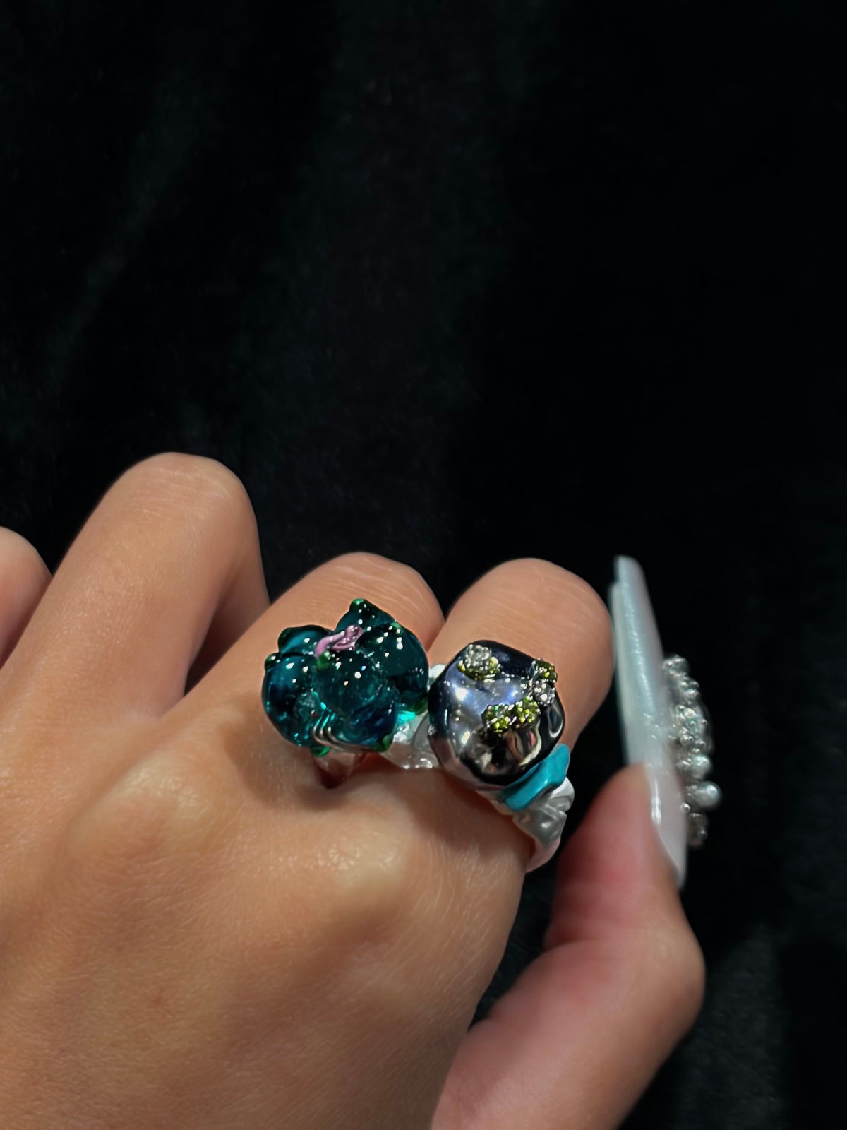Side view of a hand wearing the handcrafted teal flower ring, showing the layered beaded details and sculptural silver-tone setting