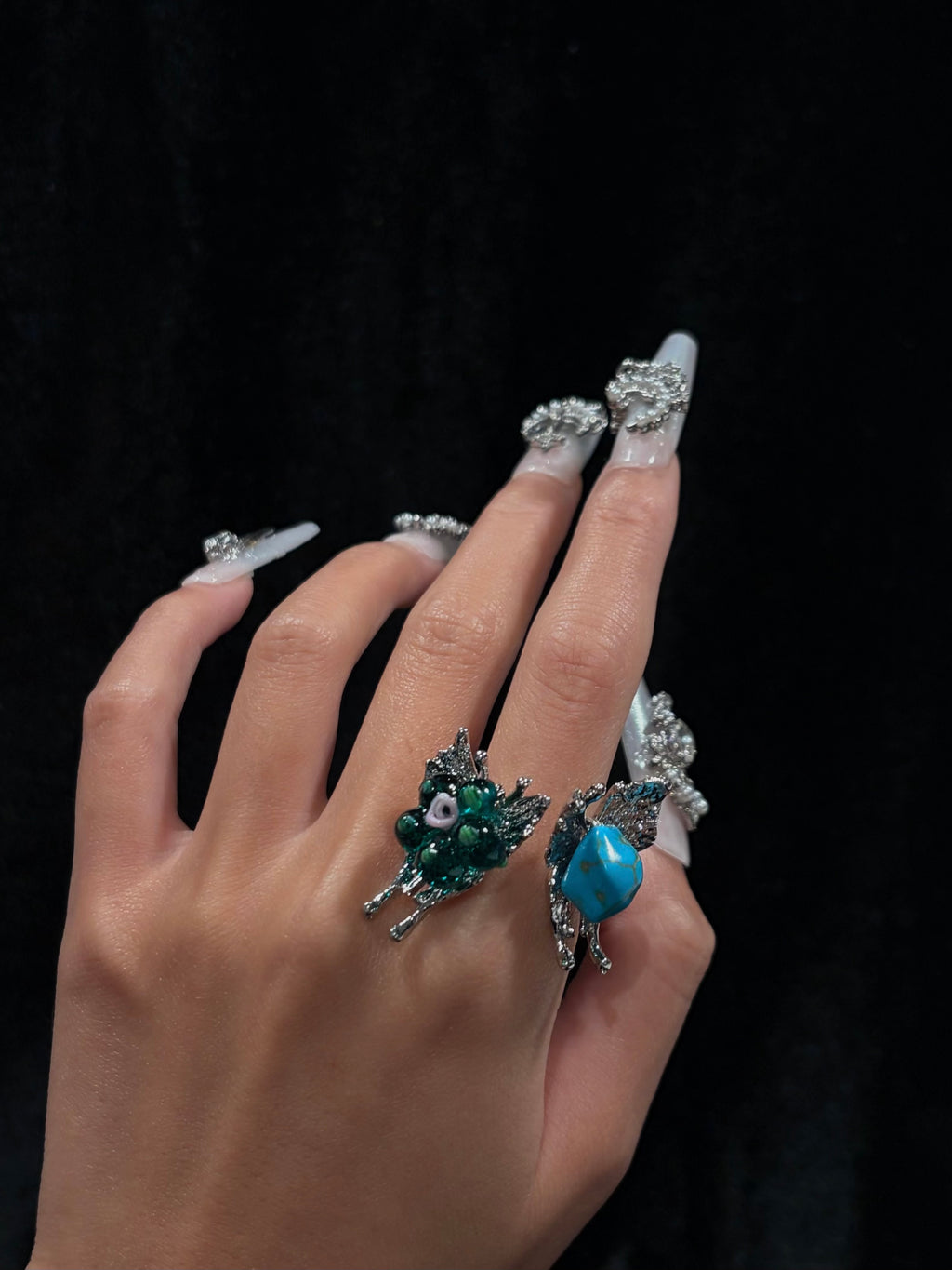 Hand wearing a handcrafted turquoise butterfly adjustable ring with teal green floral beads, turquoise-style stone and silver-tone butterfly details