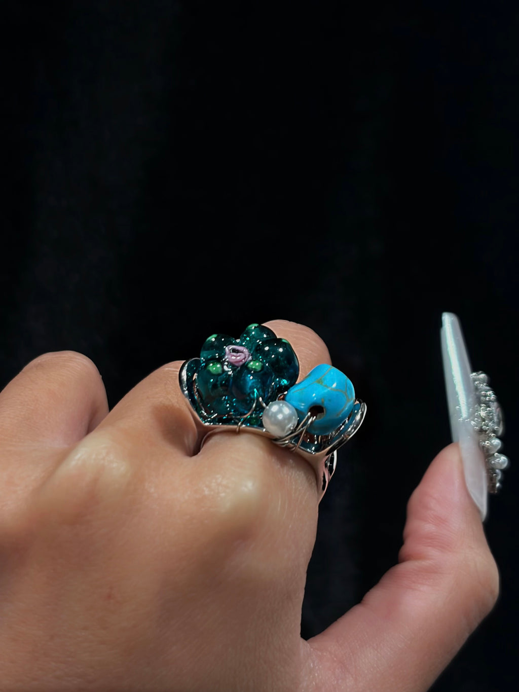 Side view of the handcrafted turquoise teal flower ring showing hand-wired floral beads, turquoise-style stone, pearl accent and sculptural silver-tone setting