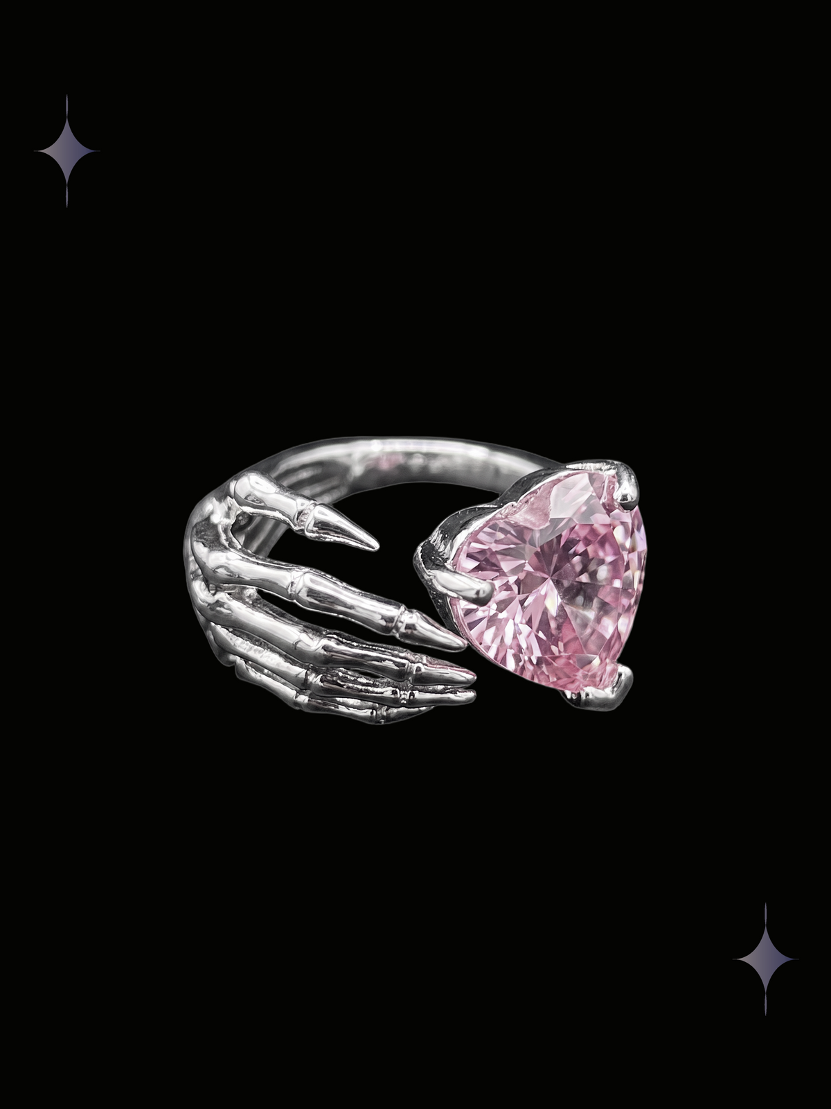 Skeleton Heart Y2K sparkling pink crystal ring with a heart-shaped cubic zirconia and sculpted skeleton hand design on a black background
