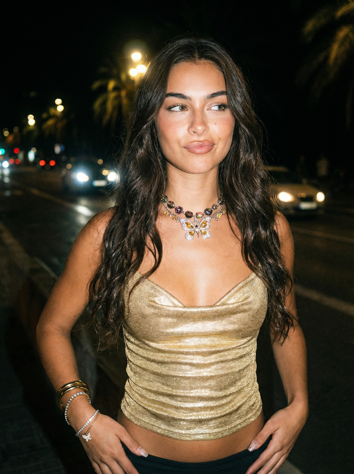 Model wearing the Sunset Glitter Y2K gold butterfly beaded necklace with colorful rose beads in a nighttime street setting